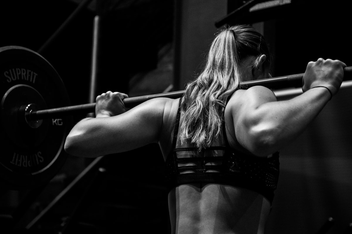 Athlete with a barbell across her back, black and white